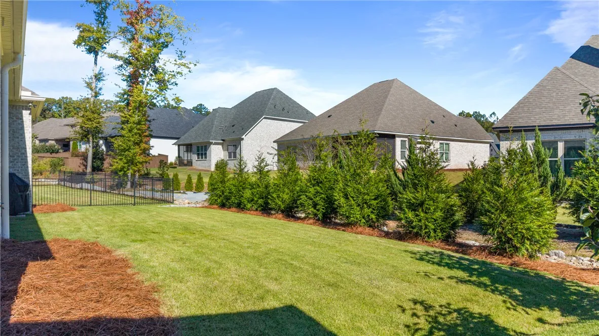 A manicured green lawn is bordered by professional landscaping and classic metal fencing.