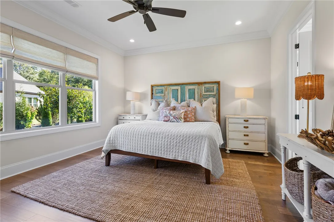 Rich hardwood floors and elegant crown molding define this serene, window-lit bedroom.