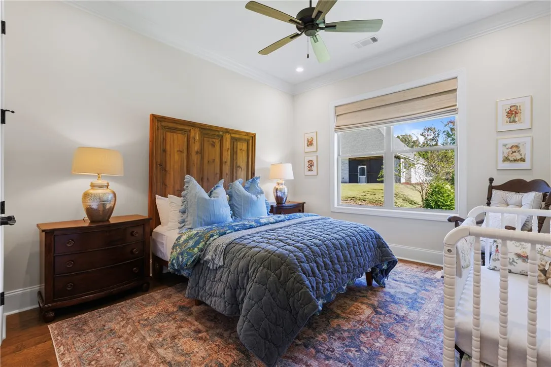 Rich hardwood flooring and crown molding frame this inviting space featuring a large window.