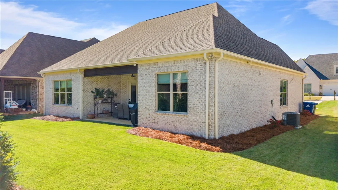 An inviting covered patio looks out over a manicured lawn bordered by classic brick architecture.
