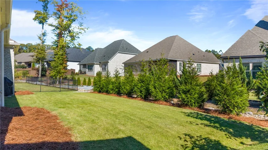 A manicured green lawn is bordered by professional landscaping and classic metal fencing.