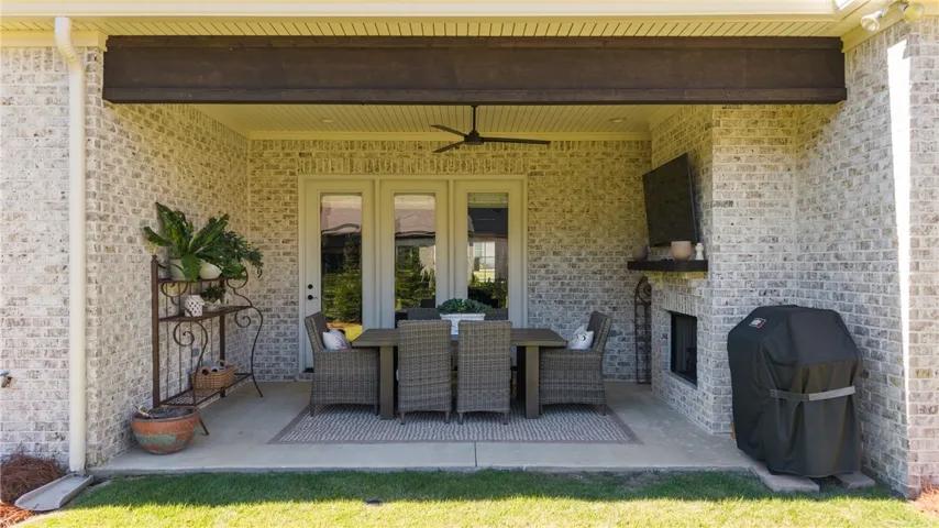 An inviting covered patio showcases light brick walls and a built-in outdoor fireplace.