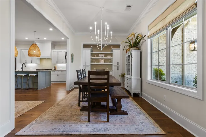 Hardwood floors and crown molding complement the open layout connecting to the kitchen.