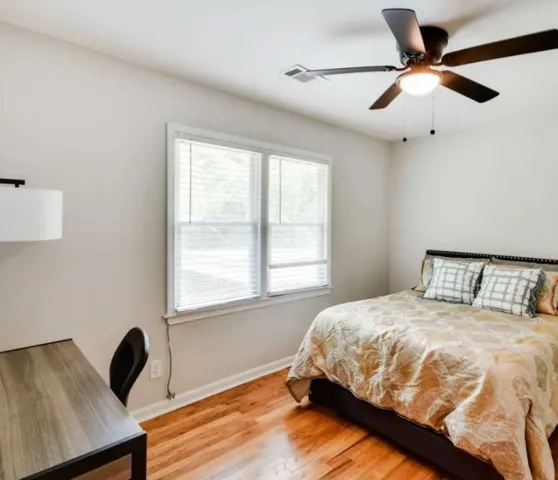 Warm hardwood flooring and classic double windows define this inviting bedroom space.
