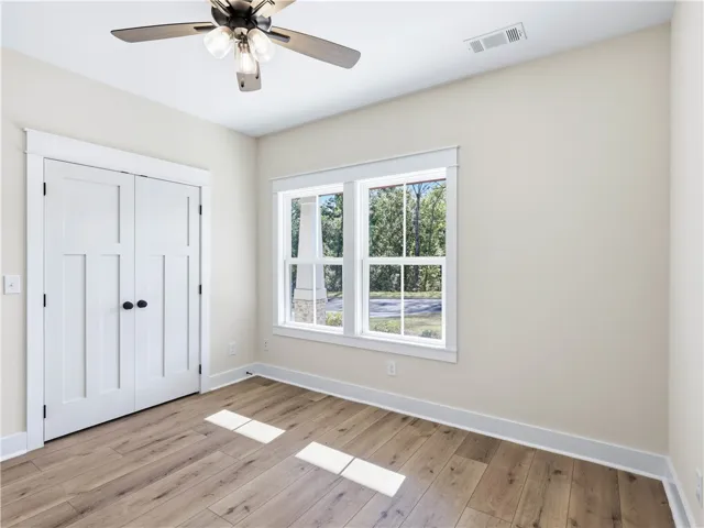 Natural light warms this serene bedroom featuring handsome wood floors and classic paneled closet doors.