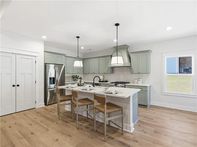 An open kitchen layout showcases custom cabinetry, stone countertops, and wide-plank wood flooring.