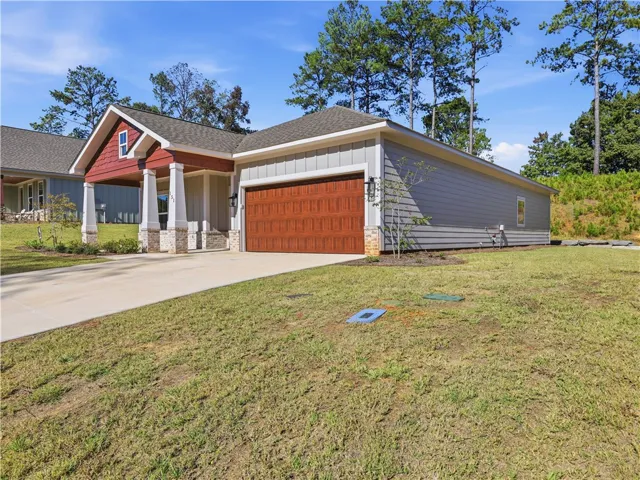 A concrete driveway leads to a wood-look garage door and a craftsman-style covered front porch.