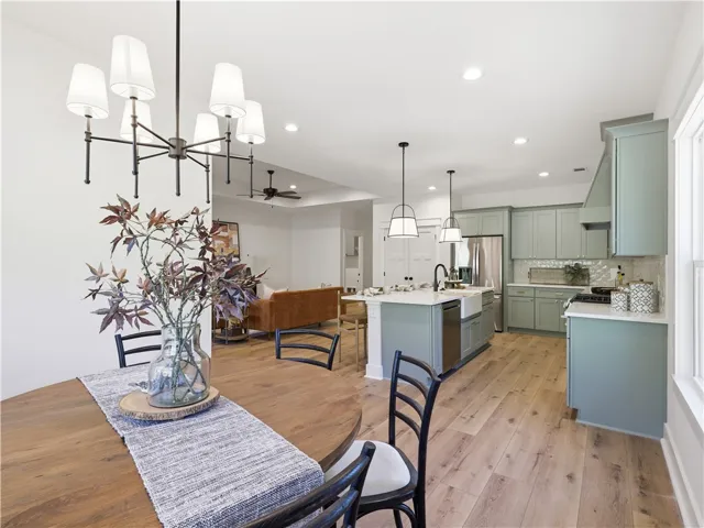 An open-concept layout connects the light-filled dining space and modern kitchen with handsome wood flooring.