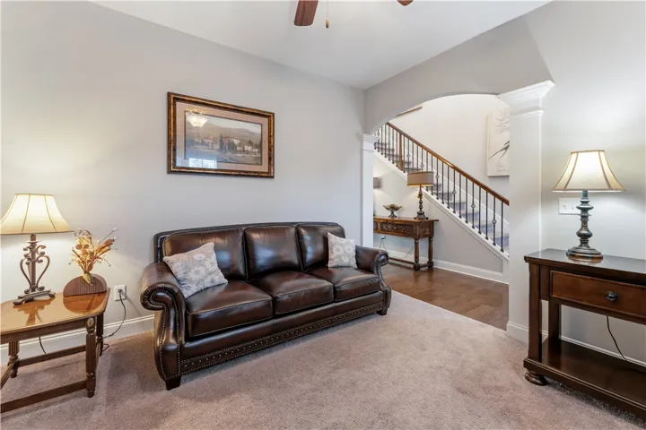 An arched doorway connects the comfortable carpeted living area to a hardwood-floored staircase foyer.