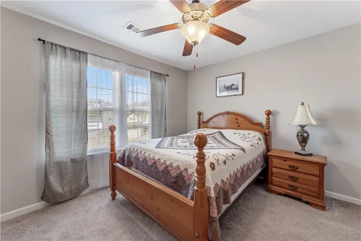 Natural light pours through wide windows, highlighting the comfortable carpet and smooth walls.