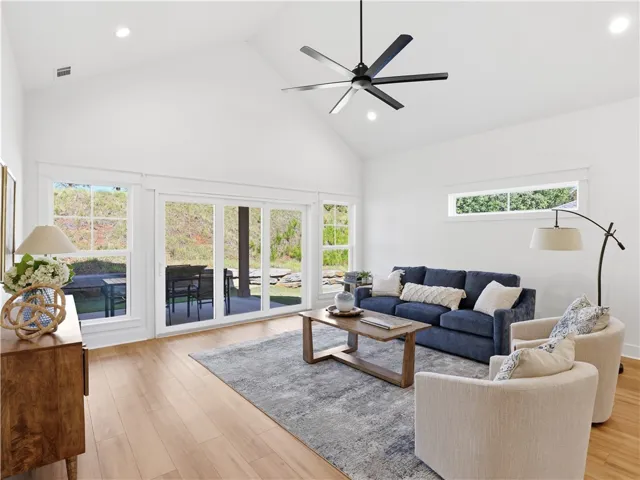 Soaring vaulted ceilings and rich wood floors anchor this open and airy living room.