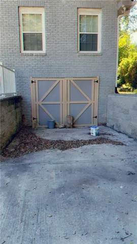 Double wooden doors lead directly into the basement level below the brick exterior.