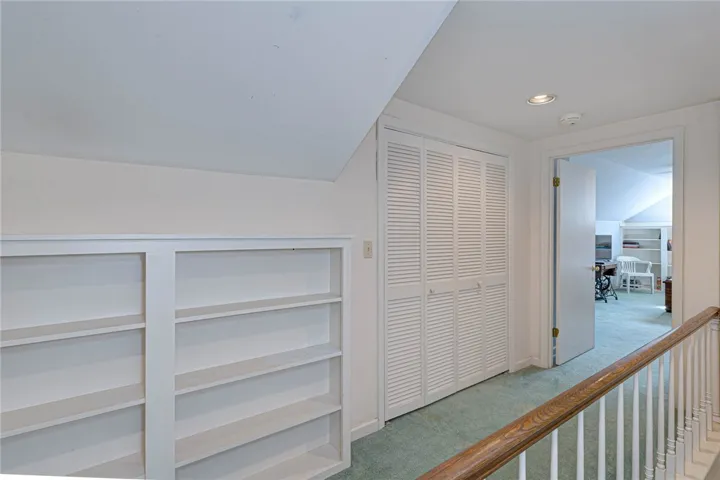 An upper landing features built-in shelving, walk-in closet with work space.