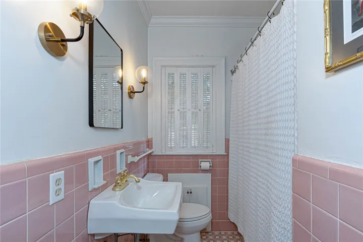 Vintage charm defines this bathroom featuring classic wall tilework, original cast-iron tub, and crown molding.