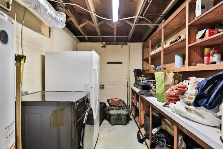 Unfinished basement utility area features extensive built-in shelving and exposed joist ceilings.
