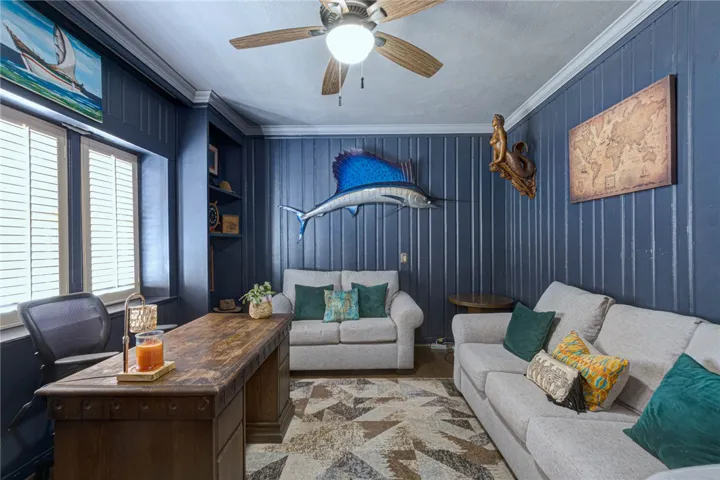 Rich wood paneling paired with classic crown molding shine in this comfortable bedroom/workspace.