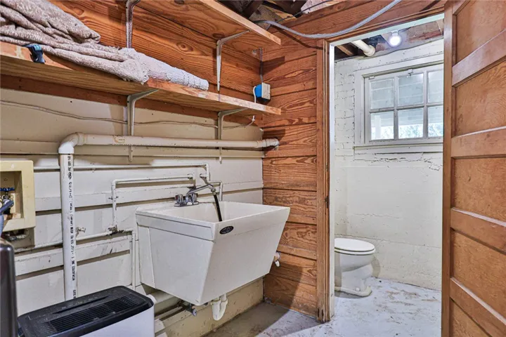 Basement utility space has  a wash sink, dehumidifier, and half bath.