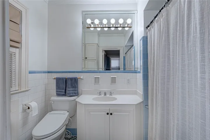 Classic tile wainscoting and a matching vanity highlight this functional primary bathroom space. And the cabinets!