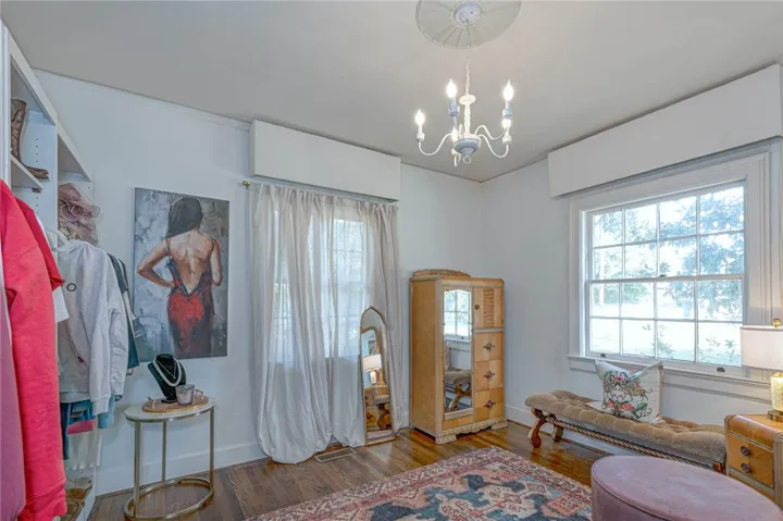 Bedroom-turned-dressing room with hardwood floors and classic multi-pane windows.