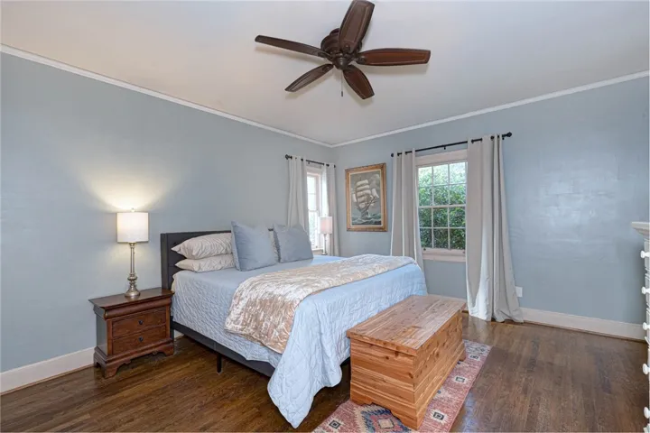 Rich hardwood floors and classic crown molding anchor this peaceful primary bedroom.