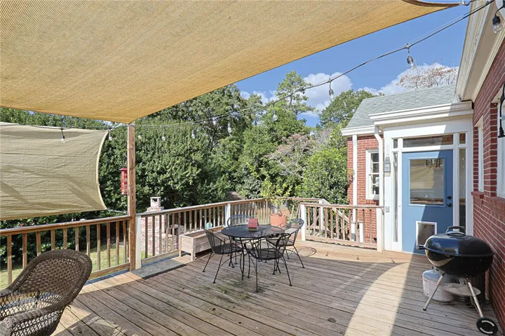 An inviting wooden deck features a dining area shaded by sail canopies.