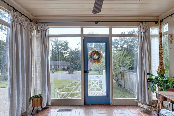 Floor-to-ceiling windows and brick flooring frame peaceful views of the surrounding neighborhood greenery.