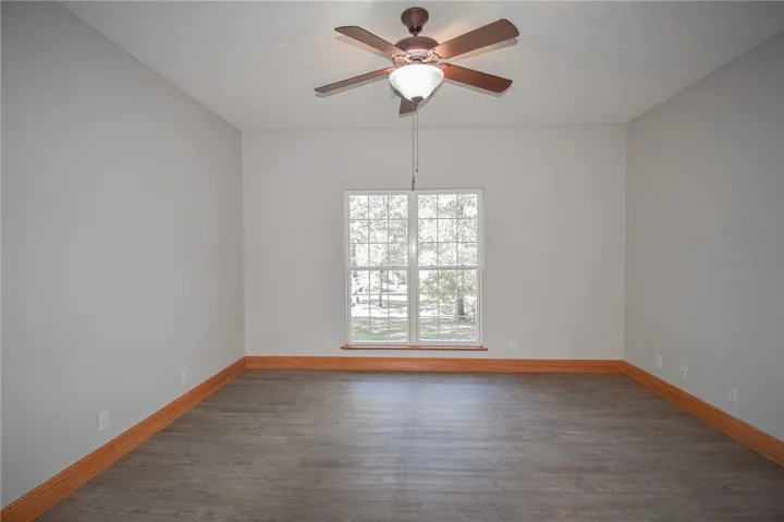 A spacious room features durable vinyl plank flooring and baseboard molding below neutral walls.