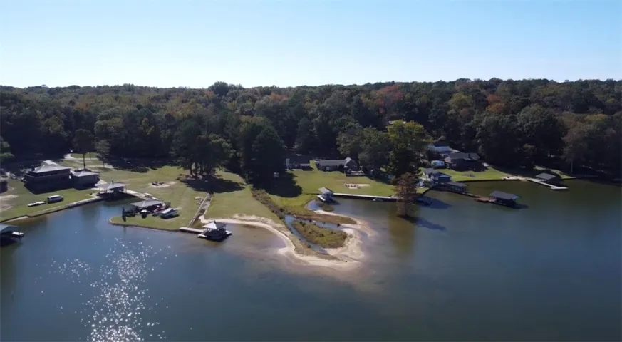 Quiet waterfront properties line the gentle shoreline under a clear blue sky.