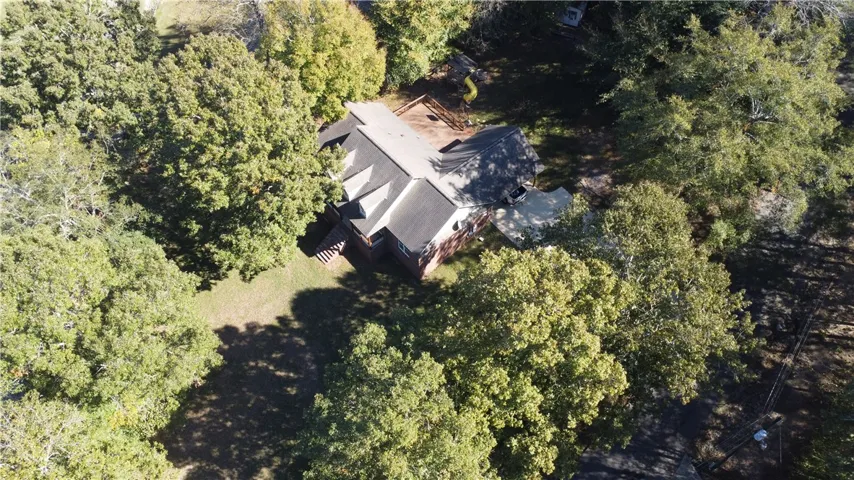 Mature trees surround this private estate featuring a multi-gabled shingle roof and brick exterior.