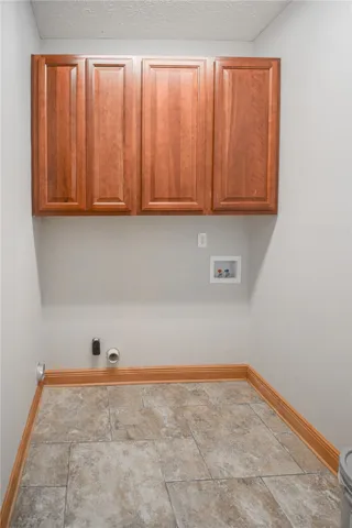 Functional utility space features warm wood cabinetry over structured tile flooring.