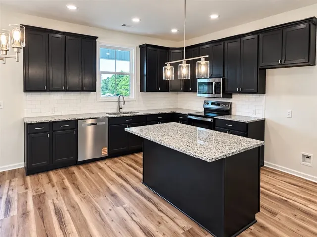 Bold dark cabinetry contrasts beautifully with granite countertops and rich wood floors in this kitchen.