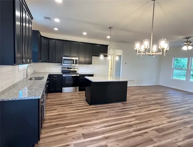 Polished stone counters and dark cabinetry anchor this open-concept culinary space.