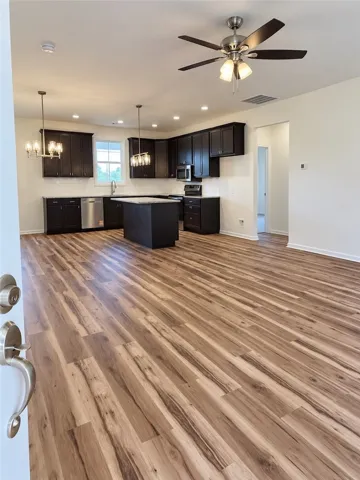 Rich wood-look flooring stretches across a modern, open-concept layout leading into the kitchen.