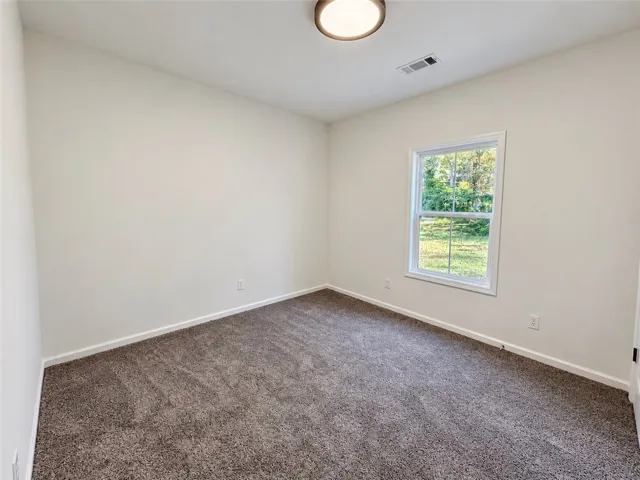 A window overlooks the backyard from this carpeted bedroom.
