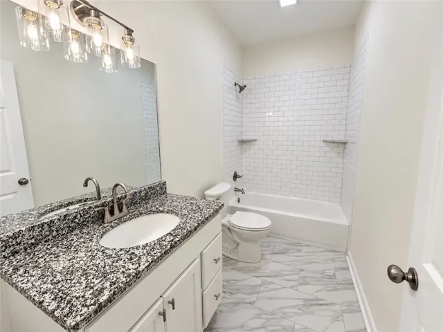 Tiled flooring and a stone vanity countertop define this modern full bathroom.