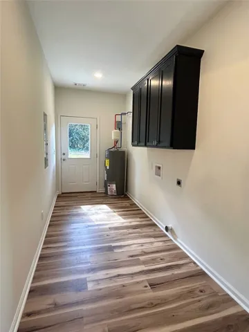 Warm wood-look flooring guides the eye toward a functional utility area with cabinetry.