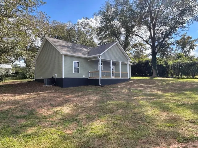 A spacious green lawn surrounds this charming home featuring a covered back porch.