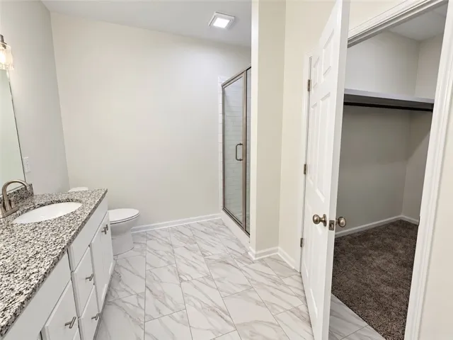 Polished tile flooring complements the stone counters and adjacent walk-in closet.