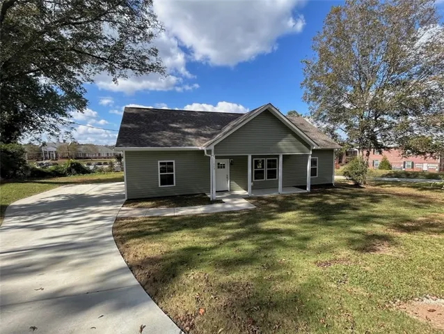 Crisp concrete pathways lead to a welcoming covered porch on this newly constructed residence.