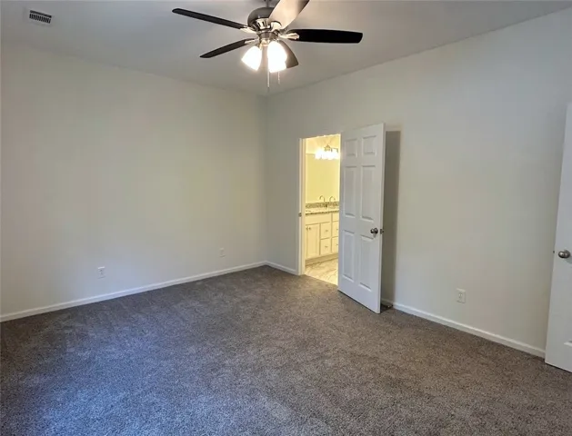A spacious bedroom featuring plush wall-to-wall carpeting and direct access to an en suite bath.