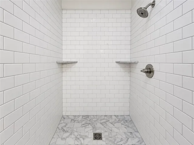 Crisp subway tile walls pair with elegant marble floor tiles in this walk-in shower.
