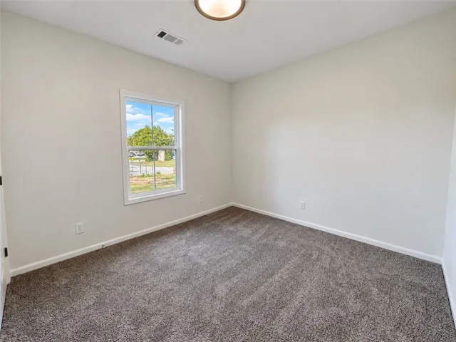 Soft plush carpeting anchors this versatile room under a clean, minimalist ceiling.