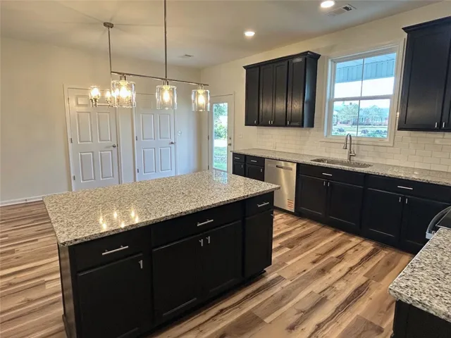 Rich dark cabinetry pairs beautifully with polished granite countertops in this modern culinary space.