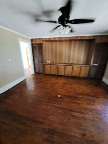 Rich hardwood flooring complements a built-in wooden media center and crown molding details.