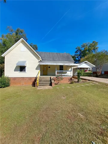 Classic vinyl and brick exterior features a covered front porch and an adjacent carport.