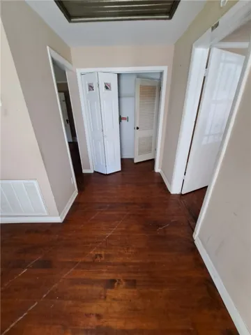 Rich wood flooring runs throughout this central hallway connecting several rooms.