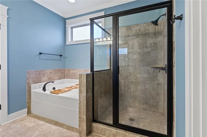 An inviting bathroom displays a modern tiled shower enclosure alongside a deep soaking tub.