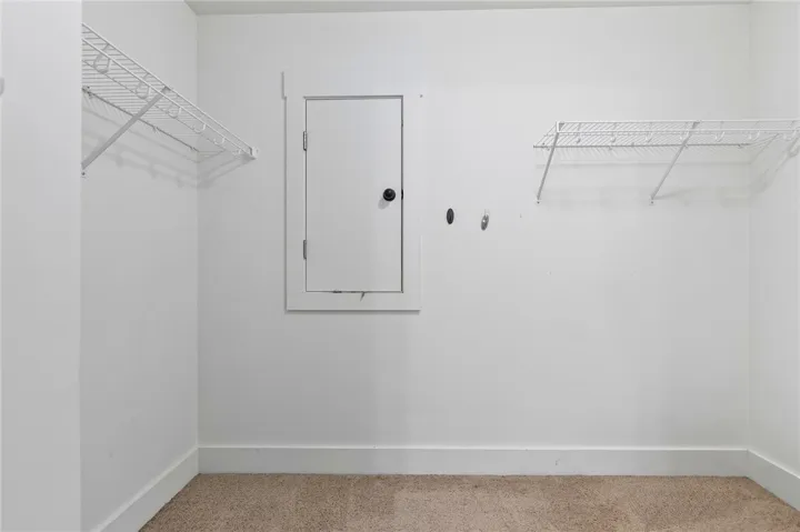 Functional closet space features practical wire shelving and neutral carpeting.