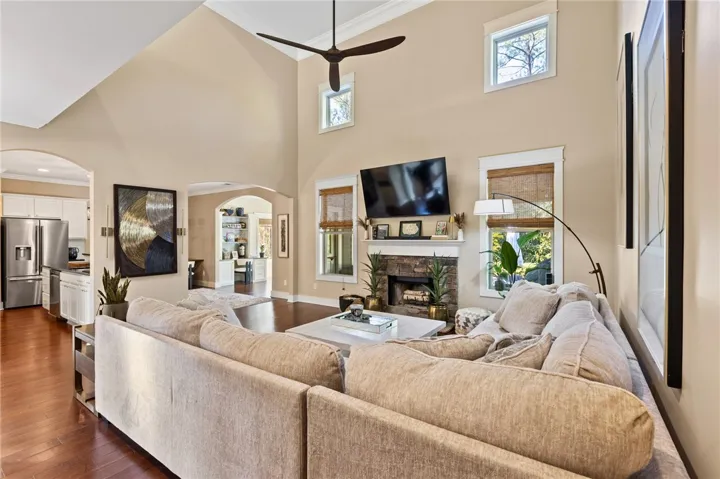 Towering ceilings and a stone fireplace anchor this light-filled main living space.