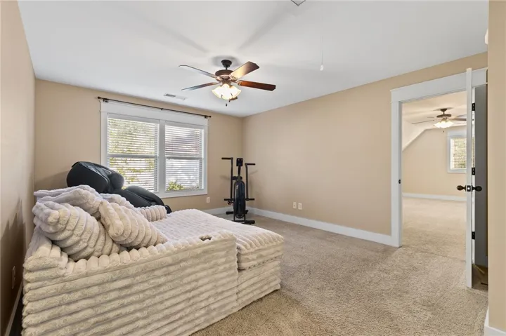 Plentiful natural light fills this cozy bedroom featuring soft carpeting and classic crown molding.